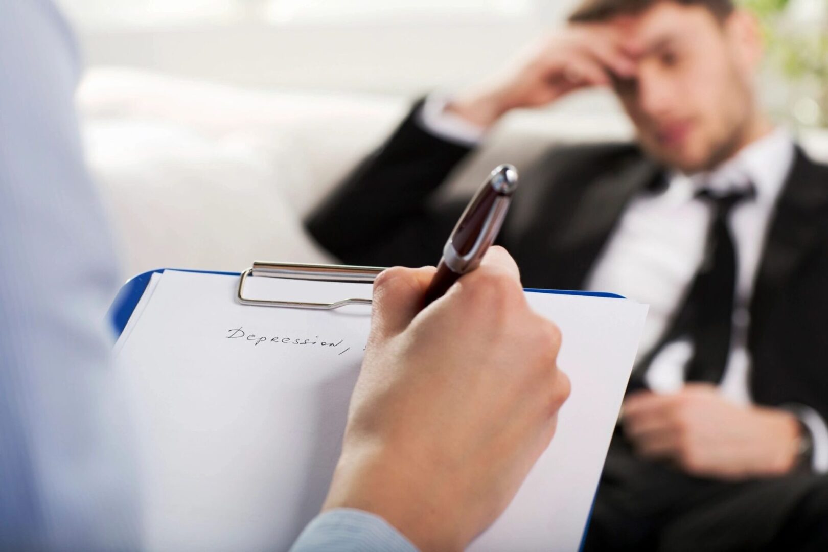 A person writing on paper with pen and clipboard.