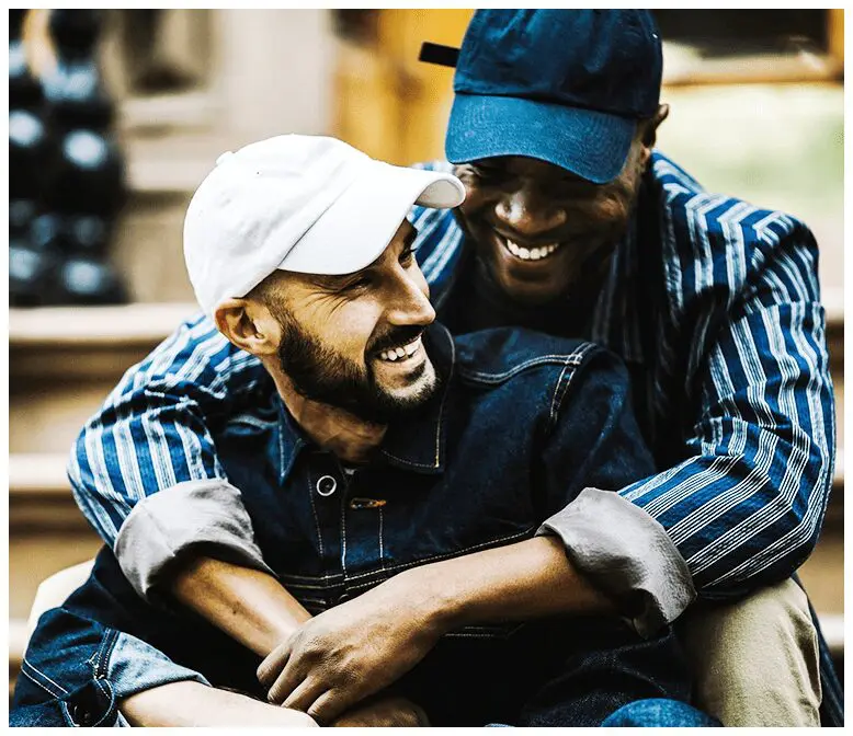 Two men sitting on a couch laughing together.